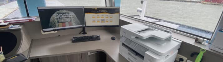 Werkplek in een stuurhuis met twee Dell-beeldschermen en een Brother-printer